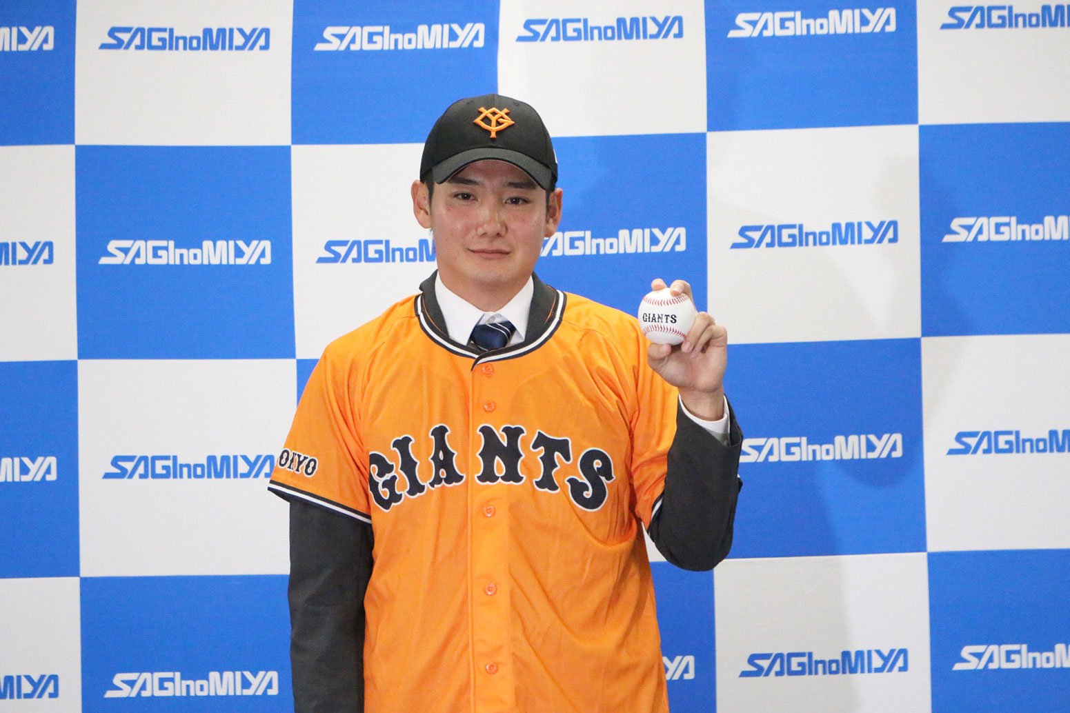 読売ジャイアンツの帽子とユニフォームを着用し、ボールを掲げました