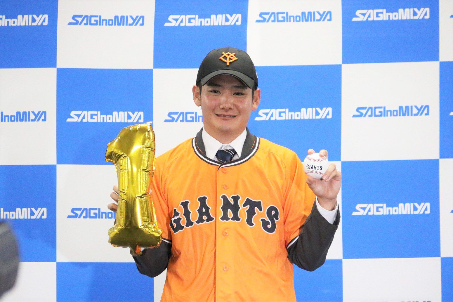 金色の「1」を手に、はにかんだ笑顔を見せました